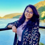 Suzzana Rafi smiling in front of a large body of water and a green mountainside